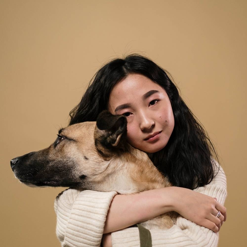 a girl hugging a brown dog